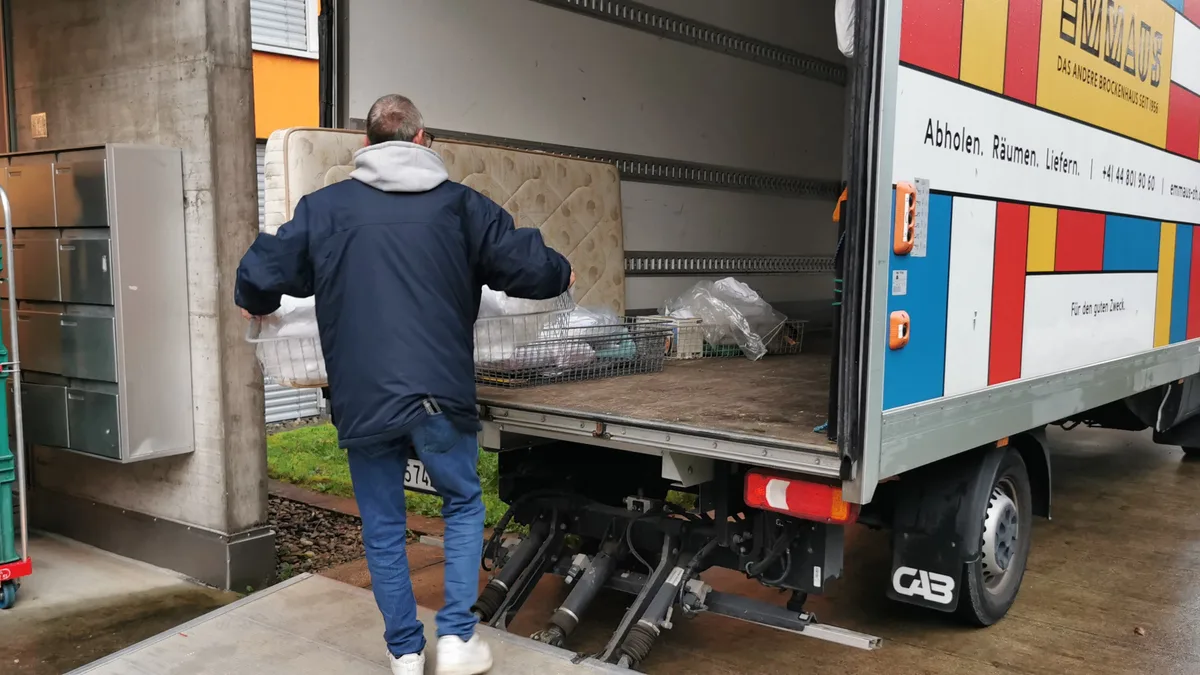 Ein Mitarbeiter des Brocki Emmaus verstaut eine alte Matraze in einem Räumungstransporter.